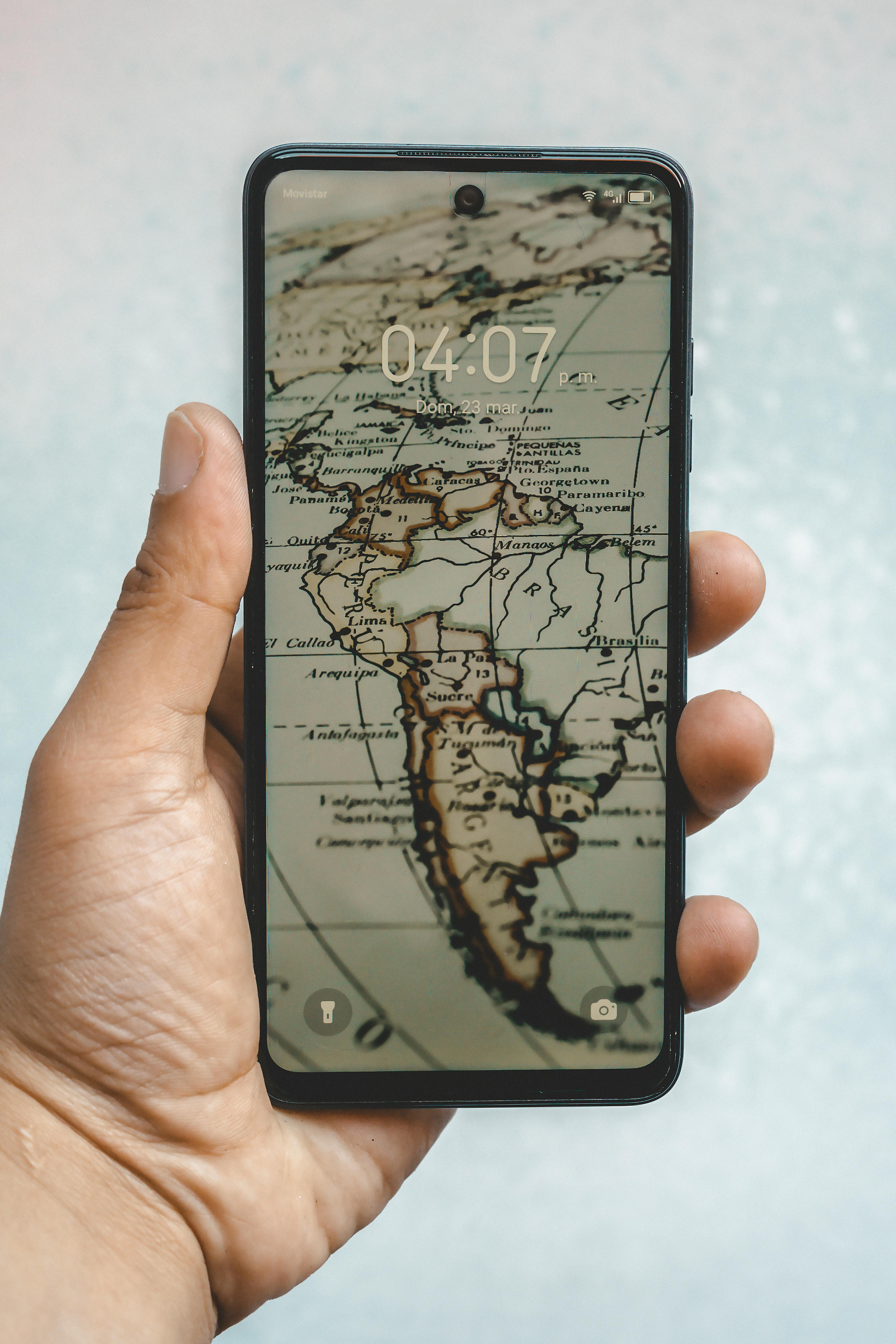 Person holding a smartphone displaying a vintage map of South America, emphasizing global connectivity.